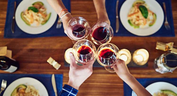 Overhead close up of four people clinking wine glasses