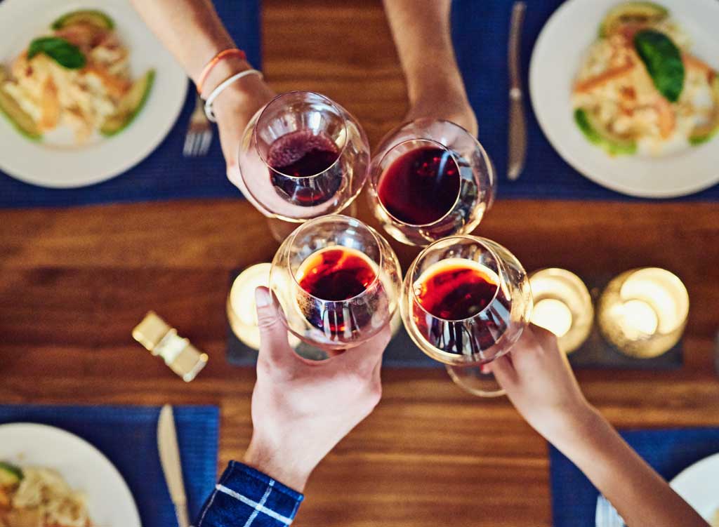 Overhead close up of four people clinking wine glasses