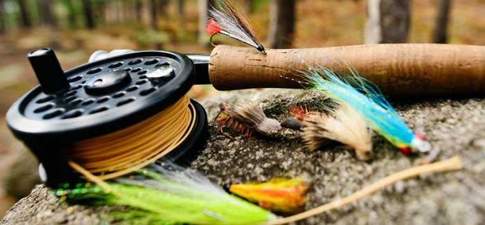 Fly fishing rod, reel and flies sitting on a rock in forest