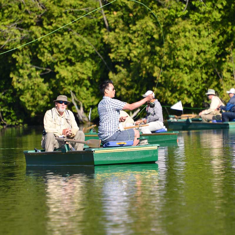 Multiple boats on lake with men fly fishing