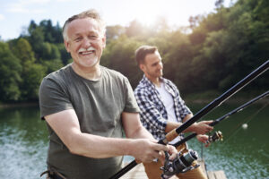 Portrait of cheerful senior man and young man fishing