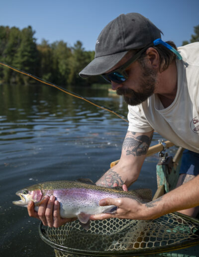 An angler looking down intently with a fish in hand on a boat.