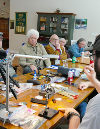A group of participants seated around a long table inside the clubhouse during an educational Smart Angling seminar.