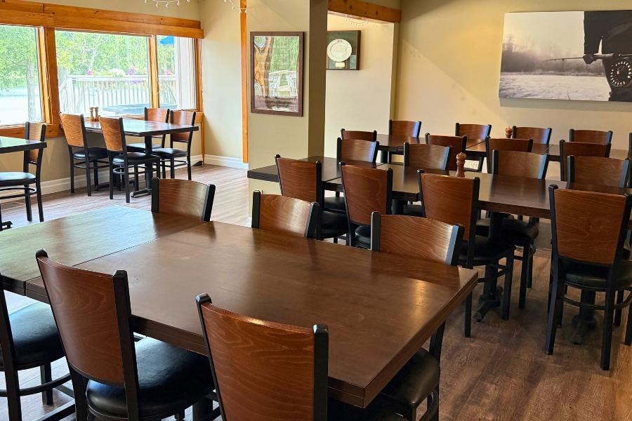 The spacious interior dining room of the Franklin Club clubhouse with wooden tables, chairs, and large bright windows.