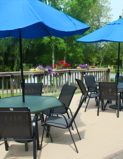 An outdoor dining patio next to the clubhouse featuring patio tables with bright blue umbrellas.
